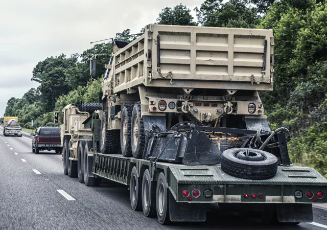 Military dump truck on flatbed trailer